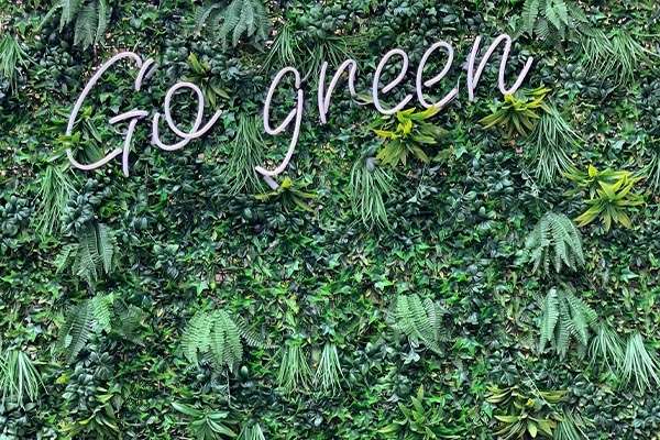 A floral green wall with neon lighting relating to environmental responsibility